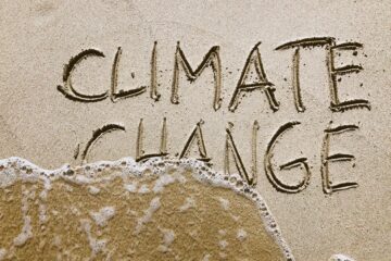 Climate change written in sand with water washing it away
