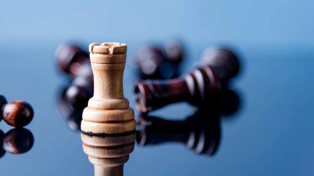 Chess pieces with rook still standing but other pieces falling to signify resilience
