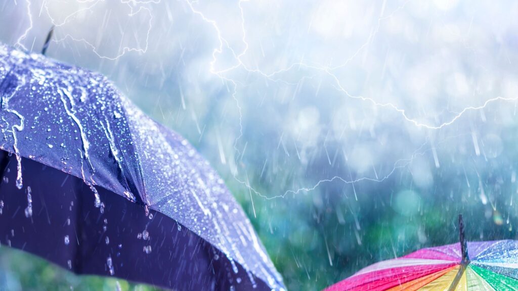 Two umbrellas up in a lightening shower